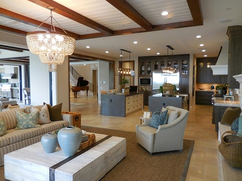 Modern living room and kitchen with chandelier and exposed beams.